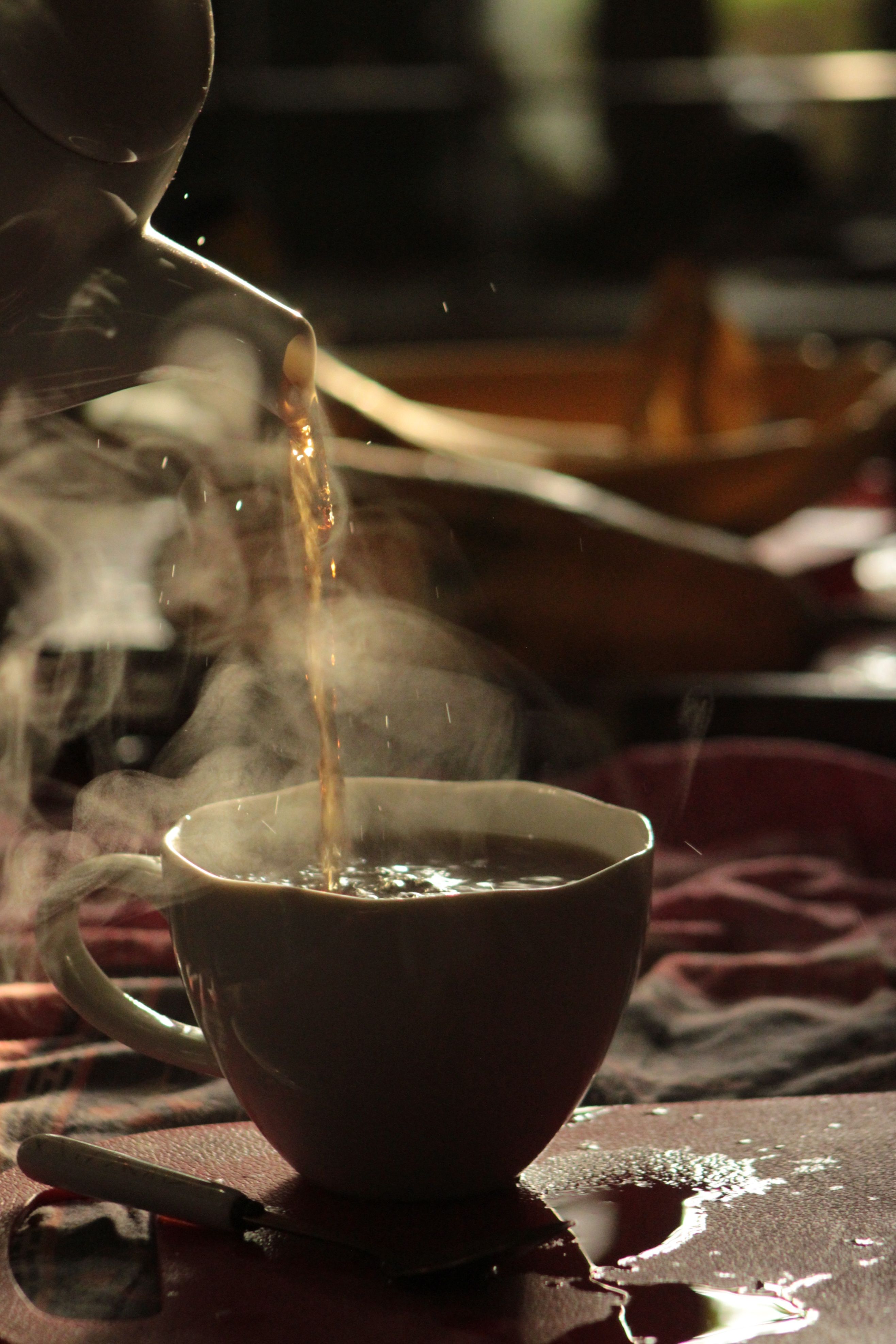 Hot black tea being poured into a steaming cup