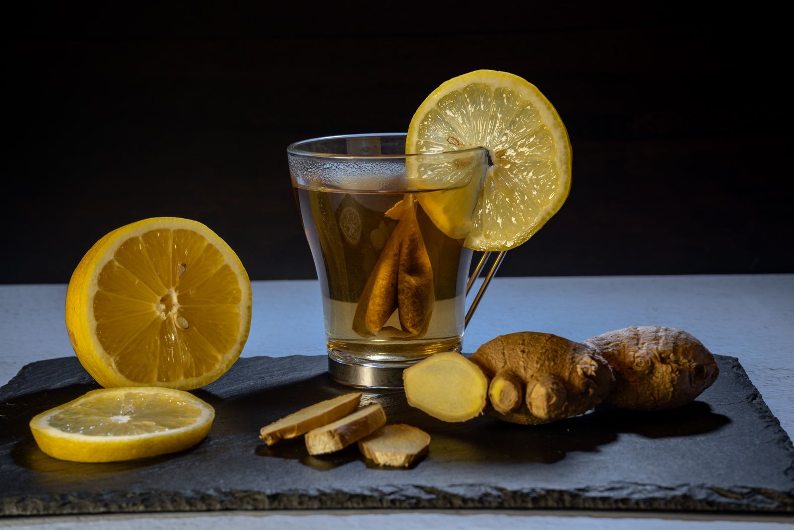 Ginger and lemon beside a freshly brewed cup of tea